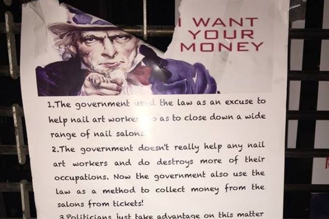 A poster on a shuttered nail salon decries the state's handling of its labor violations crackdown.